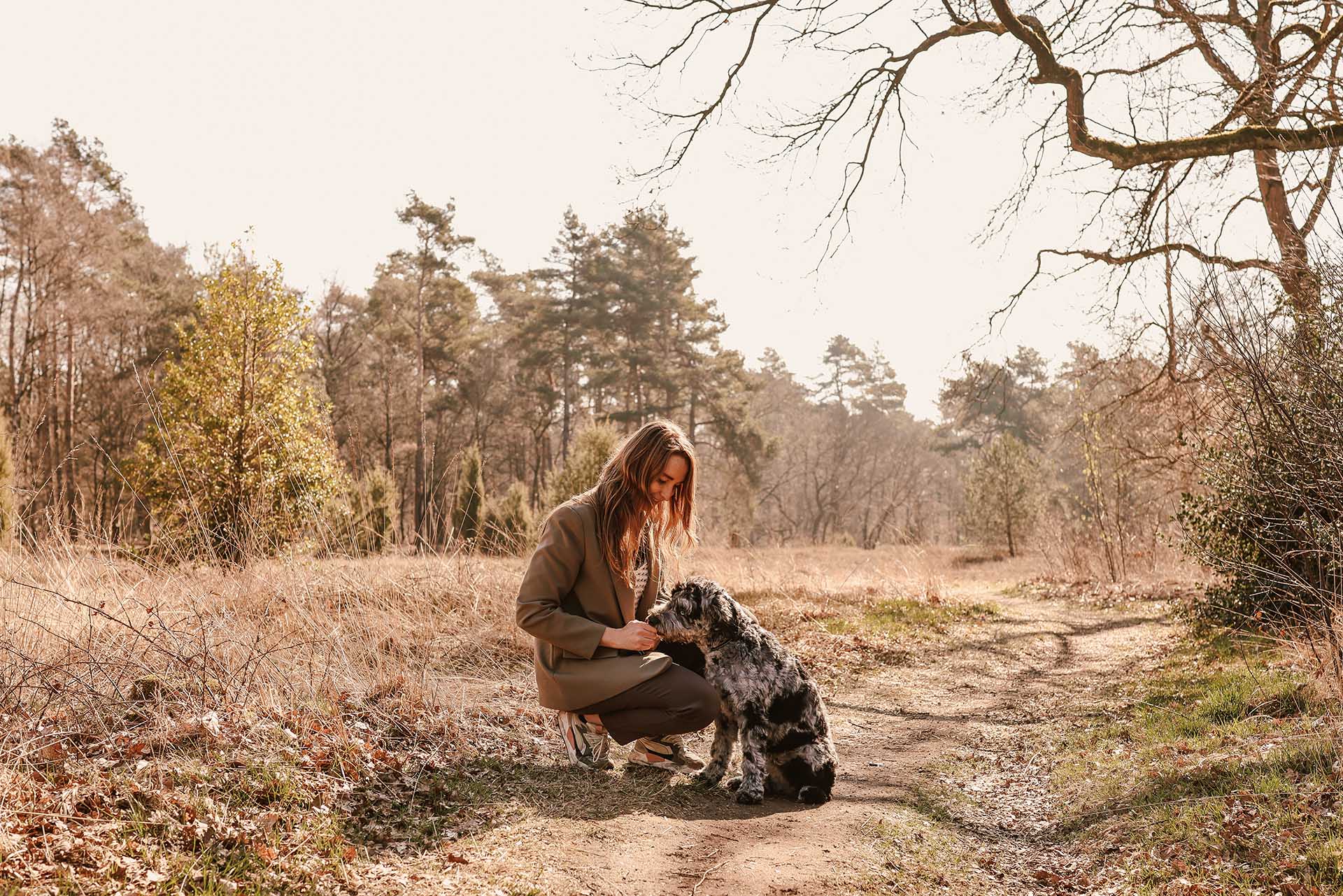 Tessa den Heeten maakt contact met haar hond op een bospad